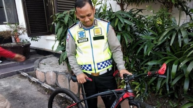 Brigadir Nathan Doris menenteng sepeda hadiah Polrestabes Bandung karena kinerjanya, Jumat (26/7/2019). (Antara/Bagus Ahmad Rizaldi)