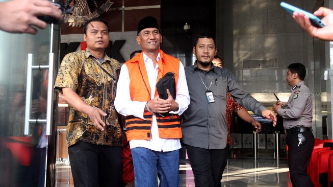 Bupati Kudus Muhammad Tamzil berjalan keluar menggunakan rompi tahanan usai menjalani pemeriksaan di gedung KPK, Jakarta, Sabtu (27/7). [Suara.com/Arief Hermawan P]