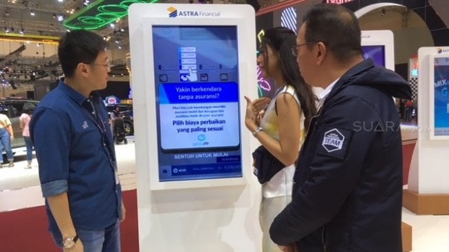 Rudy Chen (kiri) dan Gunawan Salim, para pembesar Asuransi Astra tengah mencoba simulasi kredit kendaraan dengan seorang Angel di booth Astra Financial, GIIAS 2019 [Suara.com/ukirsari].