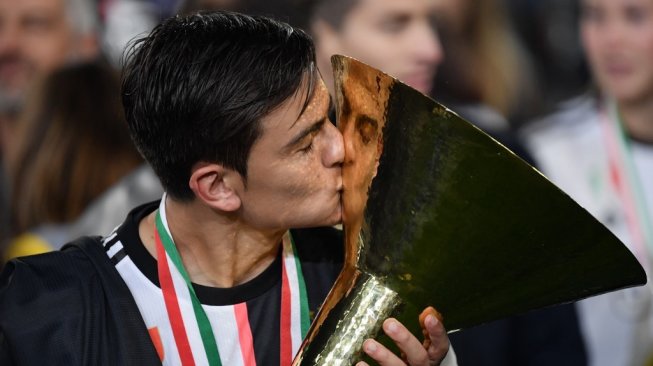 Penyerang Juventus, Paulo Dybala mencium trofi juara Liga Italia usai membawa timnya Scudetto di musim 2018/2019. [Marco Bertorello / AFP]