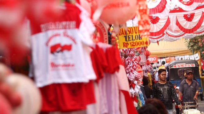 Pengunjung melintasi bendera dan umbul-umbul yang dipajang pedagang di pintu barat Pasar Jatinegara, Jakarta, Selasa (30/7). [Suara.com/Arief Hermawan P]