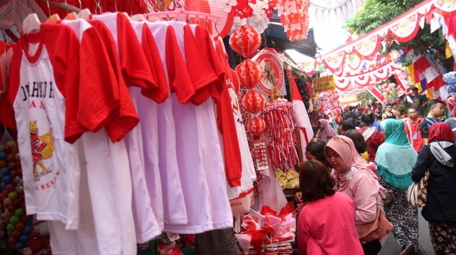 Pengunjung melintasi bendera dan umbul-umbul yang dipajang pedagang di pintu barat Pasar Jatinegara, Jakarta, Selasa (30/7). [Suara.com/Arief Hermawan P]