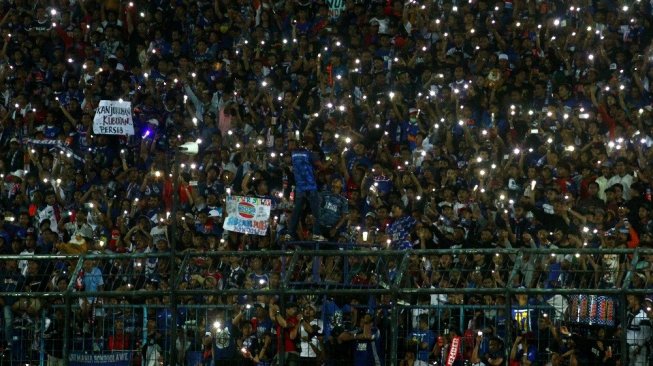 Suporter Arema FC (Aremania) beratraksi dengan menyalakan lampu gawai usai pertandingan Liga I antara Arema melawan Persib Bandung di stadion Kanjuruhan, Malang, Jawa Timur, Selasa (30/7/2019). Arema mengalahkan Persib dengan skor akhir 5-1. ANTARA FOTO/Ari Bowo Sucipto