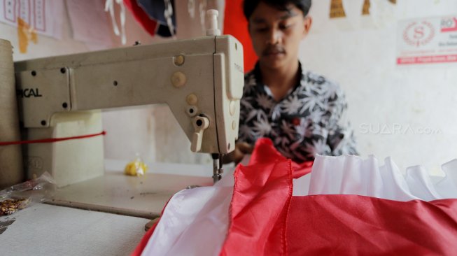 Seorang penjahit menyelesaikan pembuatan bendera merah putih di Pasar Senen, Jakarta, Kamis (1/8). [Suara.com/Oke Atmaja]