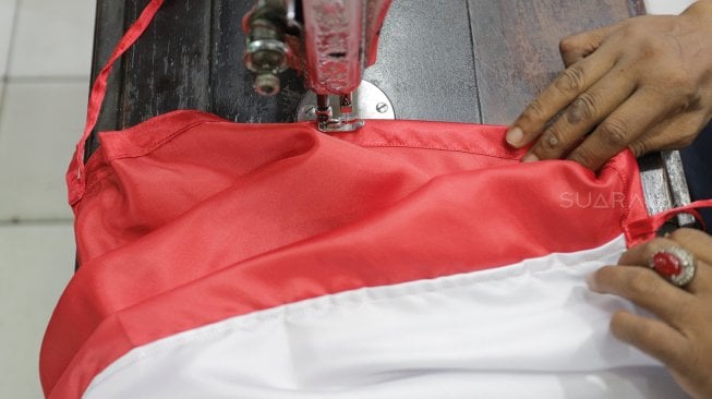 Seorang penjahit menyelesaikan pembuatan bendera merah putih di Pasar Senen, Jakarta, Kamis (1/8). [Suara.com/Oke Atmaja]