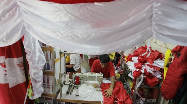 Seorang penjahit menyelesaikan pembuatan bendera merah putih di Pasar Senen, Jakarta, Kamis (1/8). [Suara.com/Oke Atmaja]