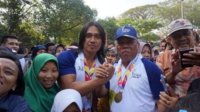 Pedangdut dan komedian Agung Hercules berfoto bersama Menteri PUPR Basuki Hadimuljono yang dikelilingi masyarakat pada gelaran Kirab Obor Asian Games 2018 di Kota Solo, Jawa Tengah, pada Kamis (19/7/2018). [Instagram/agunghercules88]