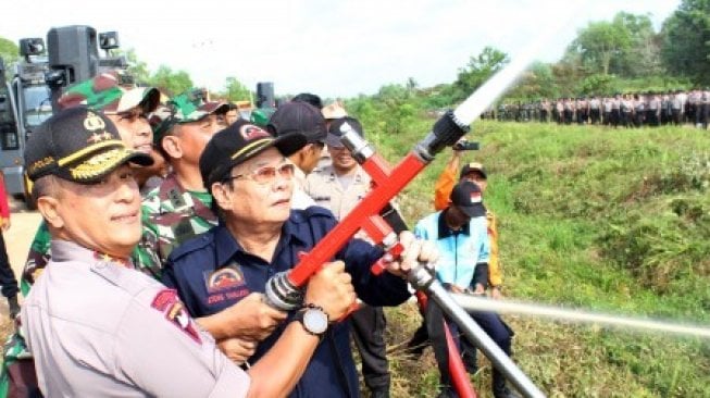 Kapolda Kalbar Irjen Pol Didi Haryono (kiri) bersama Koordinator Pemadam Kebakaran (Damkar) swasta se-Kalbar Ateng Tanjaya (kedua kiri) melakukan uji coba selang pemadam api usai apel Operasi Bina Kapuas di Kabupaten Kubu Raya, Kalimantan Barat, Rabu (24/7/2019). Dalam operasi tersebut Polda Kalbar turut melibatkan 55 Damkar Swasta se-Kalbar untuk mengantisipasi dan memadamkan kebakaran hutan dan lahan (karhutla) di 100 titik rawan hotspot di wilayah Kalbar [ANTARA FOTO/Jessica Helena Wuysang/hp].