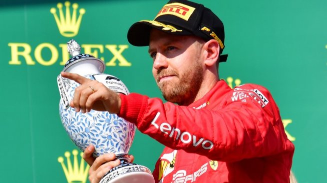 Pebalap Ferrari asal Jerman, Sebastian Vettel, merayakan keberhasilannya finis di podium ketiga balapan F1 GP Hungaria di Sirkuti Hungaroring, Minggu (4/8/2019). [AFP/Attila Kisbenedek]