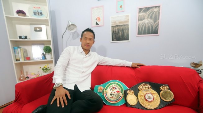Petinju Indonesia, Daud Yordan, berpose dengan sabuk juara kelas ringan super WBC International Challenge Belt yang belum ini didapatnya dan sabuk kelas ringan WBO Inter-Continental, saat berkunjung ke redaksi Suara.com, Kamis (8/8/2019). [Suara.com/Arya Manggala]