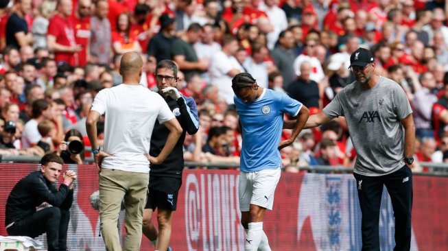 Pemain sayap Manchester City, Leroy Sane berjalan pincang ke luar lapangan setelah dilanggar pemain Liverpool saat laga Community Shield 2019 di Stadion Wembley, Minggu (4/8/2019). (Ian KINGTON / AFP)