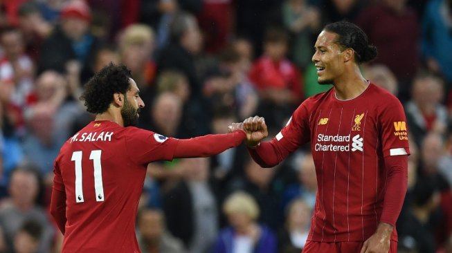 Penyerang Liverpool, Mohamed Salah merayakan keberhasilannya usai cetak gol ke gawang Norwich City bersama Virgil van Dijk, Jumat (9/8/2019). Pada laga tersebut Liverpool menang 4-1. [OLI SCARFF / AFP]