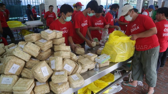 Petugas panitia hewan kurban memasukkan daging sapi ke besek bambu di Masjid Istiqlal, Jakarta, Minggu (11/8). [Suara.com/Arya Manggala]