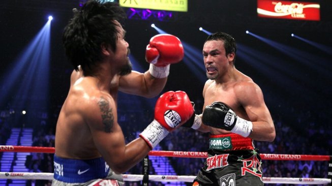 Petinju Filipina, Manny Pacquiao (kiri), terjungkal ke kanvas setelah mendapat pukulan dari rivalnya, Juan Manuel Marquez, dalam eprtarungan di MGM Grand Garden Arena, Las Vegas, AS, Sabtu (8/12/2012). [AFP/John Gurzinski]