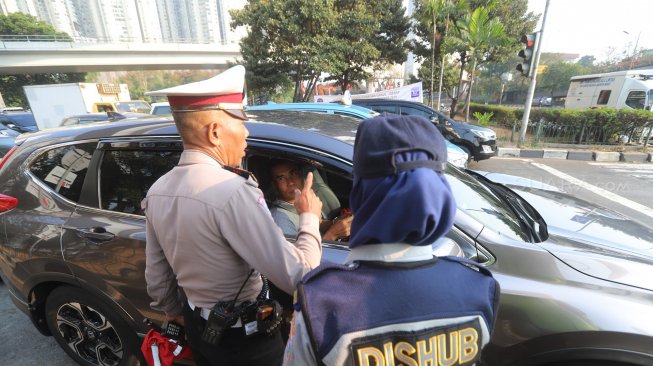 Petugas melakukan sosialisasi saat uji coba perluasan ganjil genap di kawasan Tomang, Jakarta, Senin (12/8). [Suara.com/Arya Manggala]