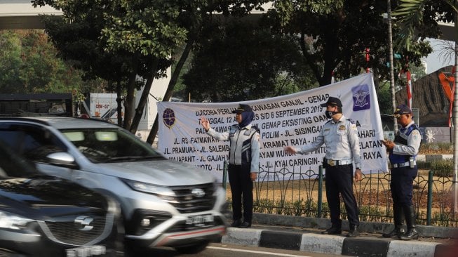 Petugas melakukan sosialisasi saat uji coba perluasan ganjil genap di kawasan Tomang, Jakarta, Senin (12/8). [Suara.com/Arya Manggala]
