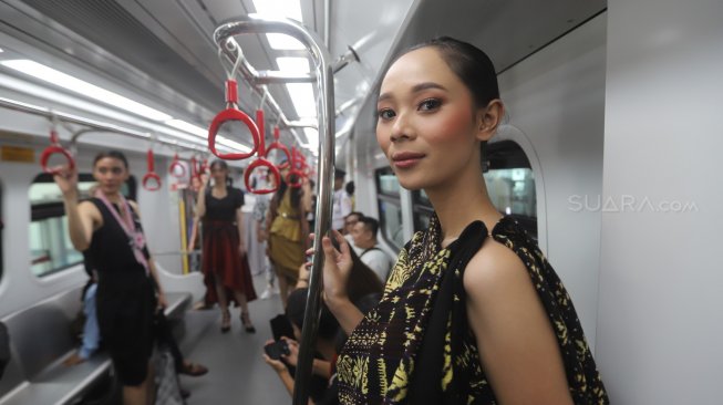 Model memperagakan busana dalam acara Jakarta Fashion & Food Festival (JFFF) 2019 di dalam gerbong LRT Jakarta jurusan Stasiun Velodrome menuju Stasiun Boulevard Utara, di Jakarta, Selasa (13/8). [Suara.com/Arya Manggala]
