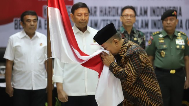 Keluarga besar Harokah Islam Indonesia, eks DI/TII dan eks NII mencium bendera merah putih, di Kantor Kemenko Polhukam Jakarta, Selasa (13/8). [Suara.com/Arya Manggala]