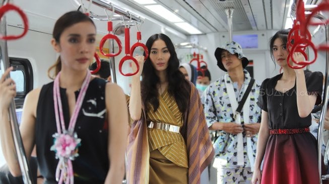 Model memperagakan busana dalam acara Jakarta Fashion & Food Festival (JFFF) 2019 di dalam gerbong LRT Jakarta jurusan Stasiun Velodrome menuju Stasiun Boulevard Utara, di Jakarta, Selasa (13/8). [Suara.com/Arya Manggala]
