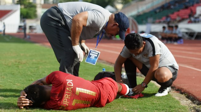Pemain Timnas Indonesia U-18 Supriadi (bawah) mendapat perawatan dari tim medis saat bertanding melawan Laos pada penyisihan Grup A Piala AFF U-18 2019 di Stadion Thong Nhat, Ho Chi Minh, Vietnam, Senin (12/8/2019). ANTARA FOTO/Yusran Uccang