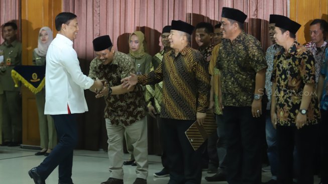 Keluarga besar Harokah Islam Indonesia, eks DI/TII dan eks NII bersalaman dengan menteri Polhukam Wiranto saat ikrar setia kepada Pancasila, UUD 1945, dan Bhinneka Tunggal Ika di Kantor Kemenko Polhukam, Jakarta, Selasa (13/8). [Suara.com/Arya Manggala]