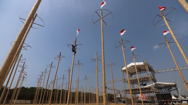 Pekerja memasang bendera merah putih pada pohon pinang untuk acara panjat pinang kolosal di kawasan Ancol, Jakarta, Rabu (14/8). [Suara.com/Arya Manggala]