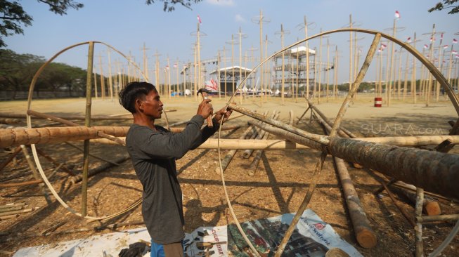 Pekerja memasang bendera merah putih pada pohon pinang untuk acara panjat pinang kolosal di kawasan Ancol, Jakarta, Rabu (14/8). [Suara.com/Arya Manggala]