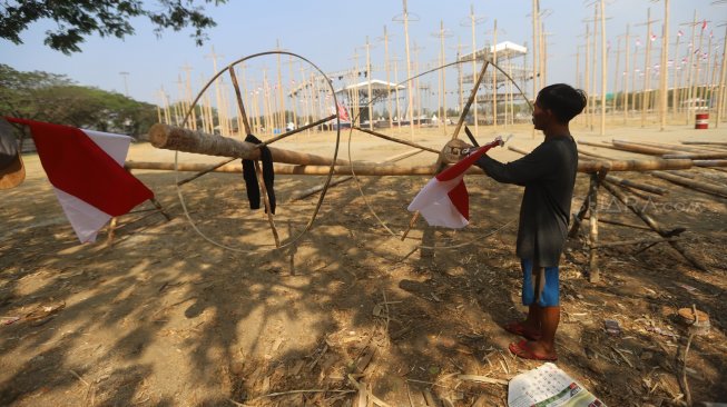 Pekerja memasang bendera merah putih pada pohon pinang untuk acara panjat pinang kolosal di kawasan Ancol, Jakarta, Rabu (14/8). [Suara.com/Arya Manggala]