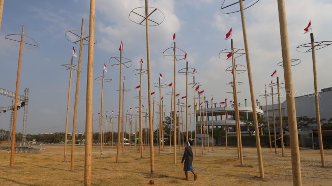 Pekerja memasang bendera merah putih pada pohon pinang untuk acara panjat pinang kolosal di kawasan Ancol, Jakarta, Rabu (14/8). [Suara.com/Arya Manggala]