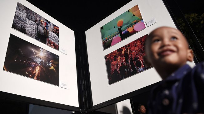 Pengunjung mengamati karya fotografi yang dipamerkan dalam pameran fotografi Rekam Jakarta di Taman Menteng, Jakarta, Kamis (15/8). [ANTARA FOTO/Aditya Pradana Putra]