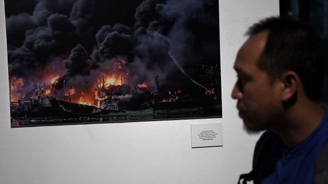 Pengunjung mengamati karya fotografi yang dipamerkan dalam pameran fotografi Rekam Jakarta di Taman Menteng, Jakarta, Kamis (15/8). [ANTARA FOTO/Aditya Pradana Putra]