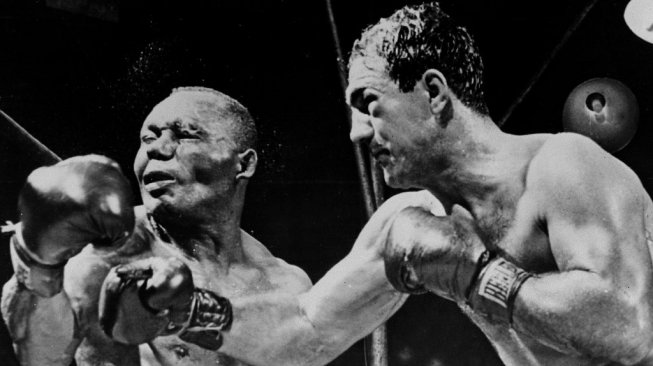 Petinju AS, Rocky Marciano (kanan), melayangkan pukulan ke arah wajah kompatriotnya, Joe Walcott, dalam pertarungan kelas berat di New York, AS pada September 1952. [AFP]