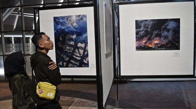 Pengunjung mengamati karya fotografi yang dipamerkan dalam pameran fotografi Rekam Jakarta di Taman Menteng, Jakarta, Kamis (15/8). [ANTARA FOTO/Aditya Pradana Putra]