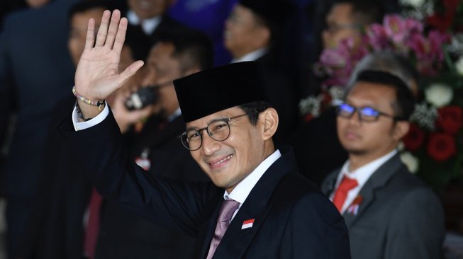 Sandiaga Uno melambaikan tangan saat tiba di Ruang Rapat Paripurna, Kompleks Parlemen, Jakarta, Jumat (16/8). [ANTARA FOTO/Puspa Perwitasari]