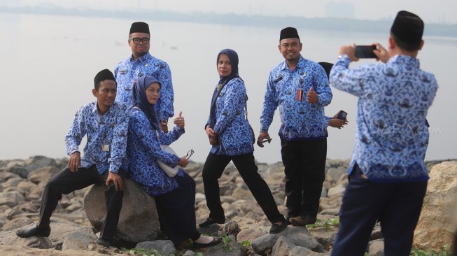 Sejumlah ASN (Aparatur Sipil Negara) Selfie di pinggir pantai usai mengikuti upacara peringatan hari kemerdekaan di Pulau D Reklamasi, Jakarta Utara, Sabtu (17/8). [Suara.com/Arya Manggala]