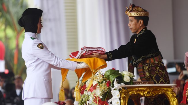 Presiden Joko Widodo (kanan) mengenakan pakaian adat Klungkung asal Bali memberikan bendera kepada pembawa baki Paskibraka dalam Upacara Peringatan Detik-Detik Proklamasi Kemerdekaan Indonesia ke-74 Tahun 2019 di Istana Merdeka, Jakarta, Sabtu (17/8). [ANTARA FOTO/Akbar Nugroho Gumay]