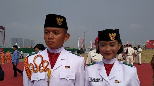 Alaia Safia, (kanan) anggota Paskibraka yang bertugas membawa baki di upacara bendera di Pulau Reklamasi yang dipimpin Gubernur DKI Jakarta. (Suara.com/Fakhri).