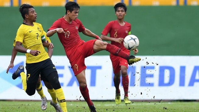 Pesepakbola Timnas Indonesia U-18, Alfendra Dewangga (tengah) berebut bola dengan pesepakbola Malaysia, Muhammad Mukhairi Ajmal (kiri) pada laga semifinal Piala AFF U-18 2019 di Go Dau Stadium, Vietnam, Sabtu (17/8/2019) petang WIB. [ANTARA FOTO/Yusran Uccang]