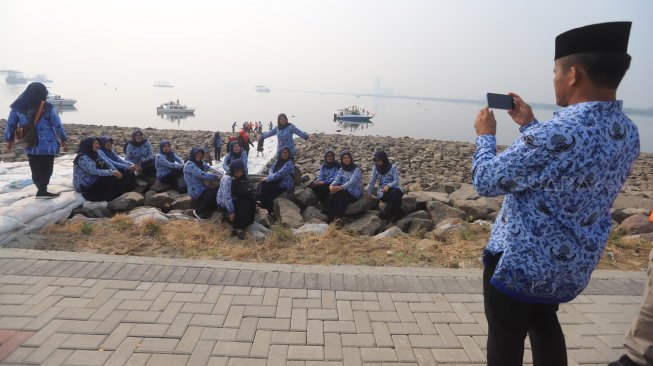 Sejumlah ASN (Aparatur Sipil Negara) Selfie di pinggir pantai usai mengikuti upacara peringatan hari kemerdekaan di Pulau D Reklamasi, Jakarta Utara, Sabtu (17/8). [Suara.com/Arya Manggala]