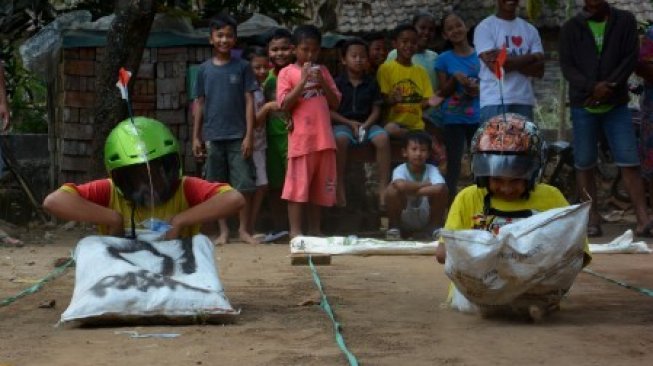 Peserta saat mengikuti lomba balap karung dengan memakai helm ala Formula 1 di Dusun Banjarsari, Desa Bareng, Kabupaten Jombang, Jawa Timur, Sabtu (17/8/2019). Para peserta yang mengikuti lomba balap karung dalam rangka peringatan hari Kemerdekaan Indonesia ini diharuskan memakai helm, dan peserta harus mencapai garis finish dengan cara ngesot tidak boleh berjalan atau lompat [ANTARA FOTO/Syaiful Arif/foc].