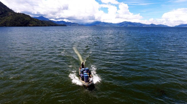 Perahu yang mengangkut drum berisi BBM  melintasi Danau Paniai menuju Kampung Obano di Distrik Paniai Barat, Papua, Kamis (29/11/2018).