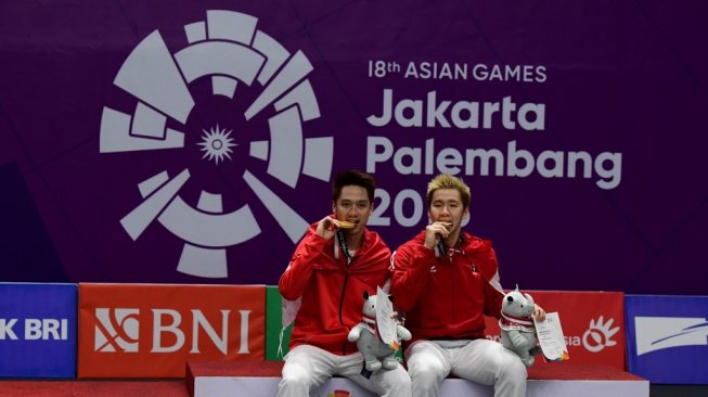 Kevin Sanjaya Sukamuljo (kiri) dan Marcus Fernaldi Gideon berpose usai meraih medali emas Asian Games 2018 di Istora Senayan, Jakarta, Minggu (28/8). [AFP/Sonny Tumbelaka]