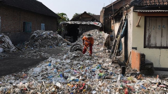 Seorang warga berpose di atas tumpukan sampah plastik impor di Desa Bangun di Mojokerto, Jawa Timur. [Zabur Karuru]