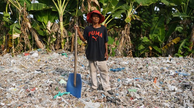 Seorang warga berpose di atas tumpukan sampah plastik impor di Desa Bangun di Mojokerto, Jawa Timur. [Zabur Karuru]