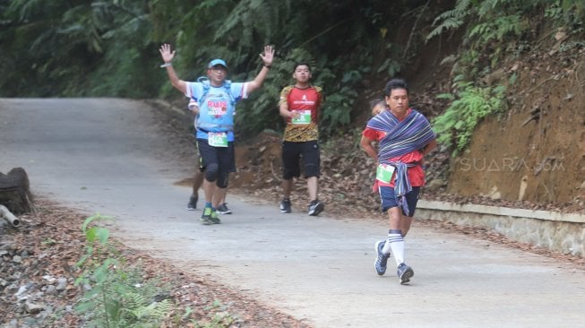 Lorenso Sutanto menggendong anaknya saat mengikuti lomba lari Situ Gunung Trail Run (SGTR) 2019 di Situ Gunung, Sukabumi, Jawa Barat, Minggu (25/8). [Suara.com/Arya Manggala]