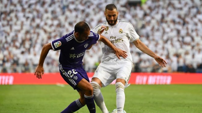 Penyerang Real Madrid, Karim Benzema mengelabui pemain Real Valladolid pada lanjutan Liga Spanyol 2019/20 di Stadion Bernabeu, Minggu (25/8/2019). (GABRIEL BOUYS / AFP)