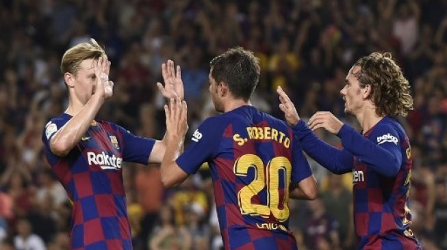 Antoine Griezmann (kanan) merayakan golnya ke gawang Real Betis bersama pemain Barcelona lainnya Sergi Roberto dan Frenkie De Jong di Camp Nou. Josep LAGO / AFP