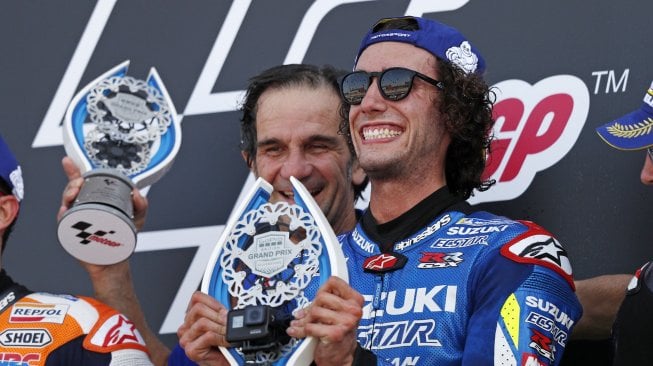 Pembalap Spanyol Suzuki Ecstar, Alex Rins, memegang trofi di podium saat ia merayakan kemenangannya dalam balapan Moto GP Grand Prix Inggris di sirkuit Silverstone di Northamptonshire, Inggris, Minggu (25/8). [Adrian DENNIS / AFP]