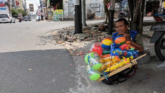 Setu, penjual balon disabilitas berteduh di Jalan Gatot Subroto, Solo, Selasa (27/8/2019). [Suara.com/Ari Purnomo]