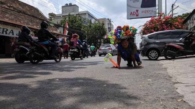 Tak Bisa Berjalan, Setu Terus Merangkak Menjual Balon Demi Nafkahi Keluarga